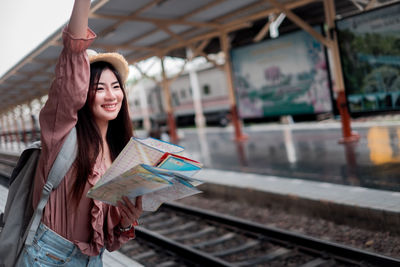 Portrait of smiling woman holding railroad station