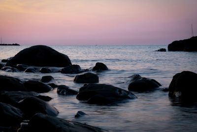 Rocks on beach against sky during sunset