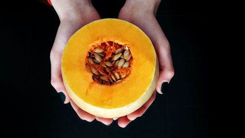 Midsection of woman holding apple against black background