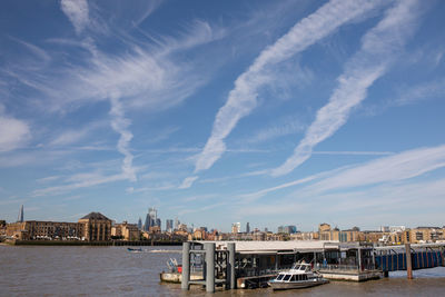 View of buildings by sea against cloudy sky