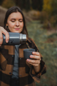 Young woman holding drink while standing outdoors