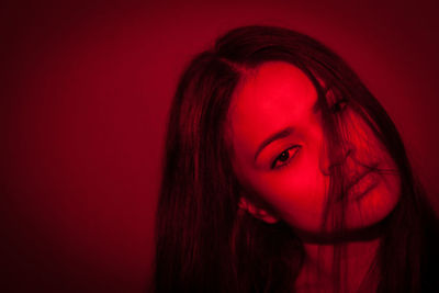 Close-up of young woman against red background