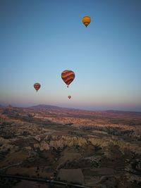 Hot air balloons flying over landscape against blue sky
