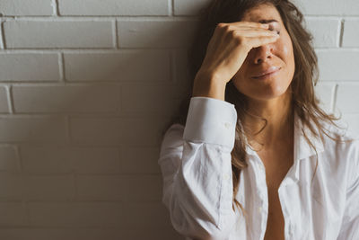 Sad woman crying against white wall