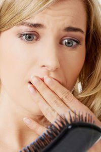 Close-up of tensed woman looking at hairbrush