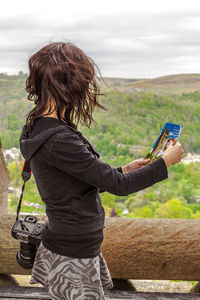 Rear view of woman holding umbrella against sky