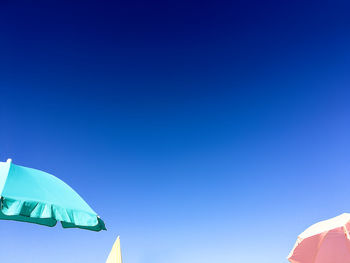 Low angle view of flags against clear blue sky