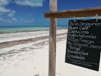 Information sign on beach against sky