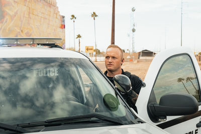 Horizontal image of white male caucasian police officer standing in the door opening of his trooper 