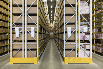 Empty narrow aisle amidst racks at distribution warehouse