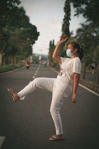Full length of young woman standing on road