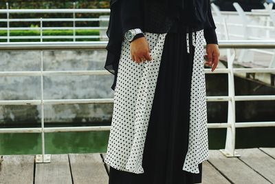 Midsection of woman standing on footbridge