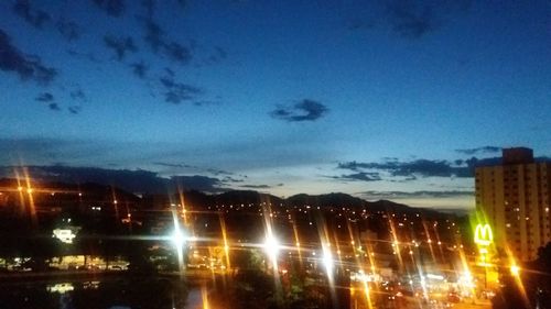 Illuminated cityscape against blue sky