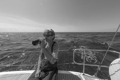 Man drinking  in sea against sky