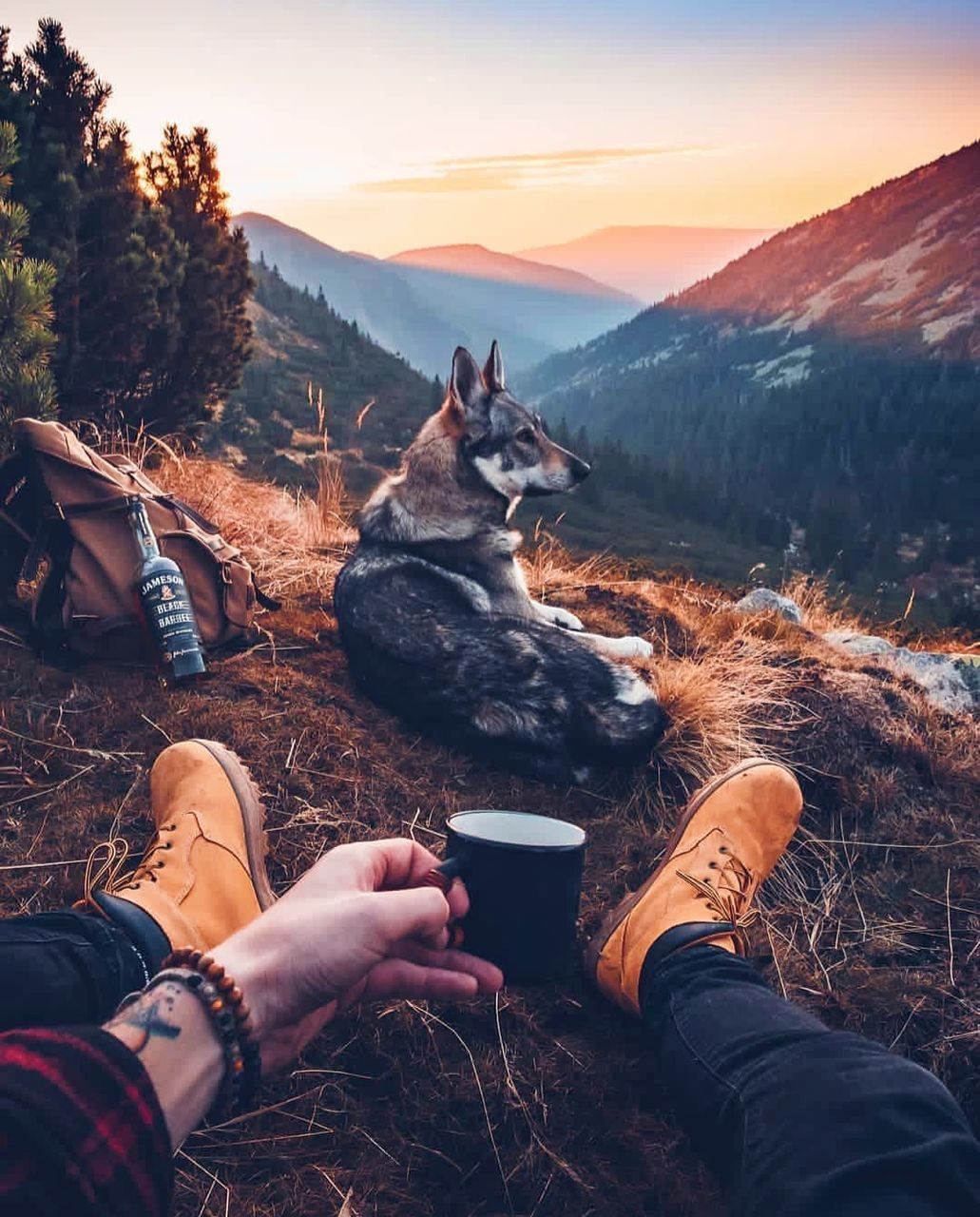 MIDSECTION OF MAN SITTING ON MOUNTAIN AGAINST SKY