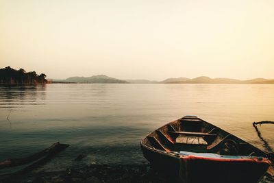 Boat moored in sea against sky during sunset