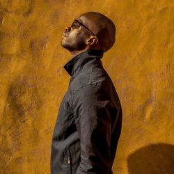 Side view of man standing against yellow wall during sunny day