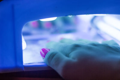 Cropped hand of woman under illuminated lighting equipment