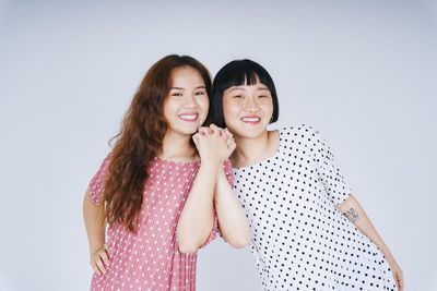 Portrait of happy lesbian couple against gray background