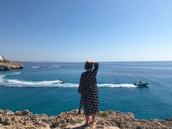 Rear view of man looking at sea against clear sky