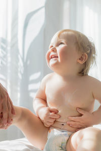 The kid rubs the tummy with cream before the massage. close-up.