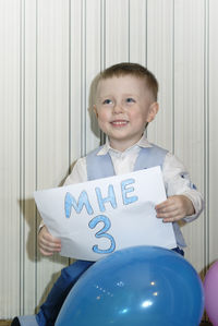 Smiling boy holding text on paper during birthday celebration