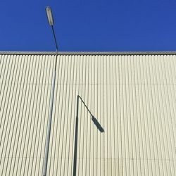 Low angle view of factory against clear blue sky during sunny day