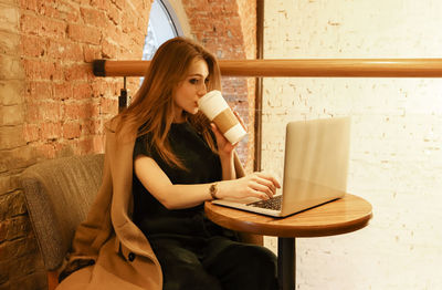 Young woman using mobile phone while sitting at home