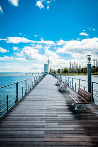 Empty pier over sea against blue sky