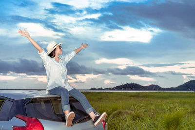 Woman with arms raised against sky