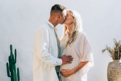 Happy pregnant couple in love kissing and hugging outdoors.