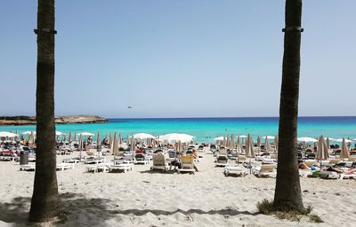 Panoramic view of people on beach against clear blue sky