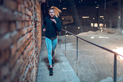 Fit young woman jogging in abandoned warehouse