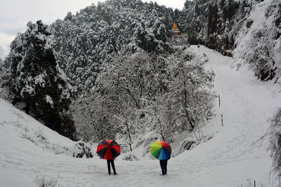 Rear view of people on snow covered field