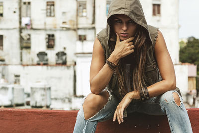 Portrait of young woman standing against wall