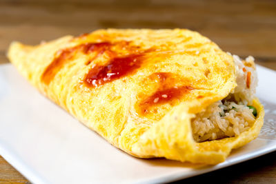 Close-up of omelet and rice wrap served in plate on table