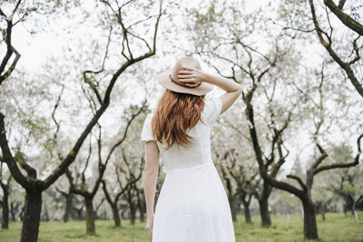 Young woman standing by tree