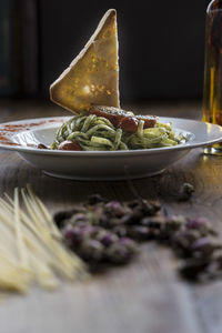 Close-up of bread slice garnished on spaghetti pasta served in bowl on table