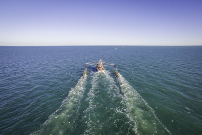 Boat sailing on sea against clear blue sky