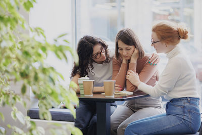 Friends consoling partner at cafe