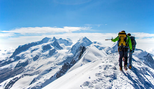 Rear view of friends standing on snow covered mountain