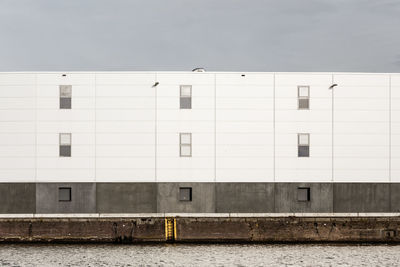 White building by river against sky