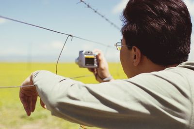 Close-up of young woman using mobile phone against sky