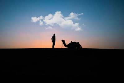 Silhouette men on stage against sky during sunset