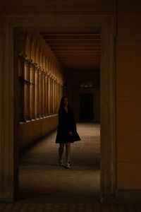 Full length of young woman standing in dark corridor