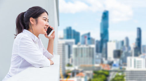 Side view of a young woman looking at city