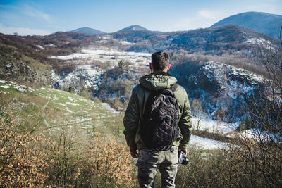 Rear view of people walking on mountain against sky