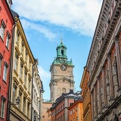 Low angle view of clock tower amidst buildings in city against sky