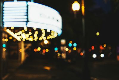 Defocused image of illuminated ferris wheel at night