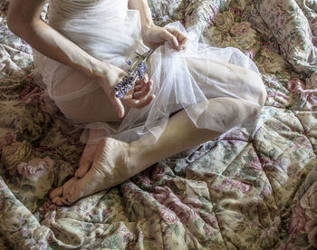 High angle view of young woman holding flowers while sitting on bed